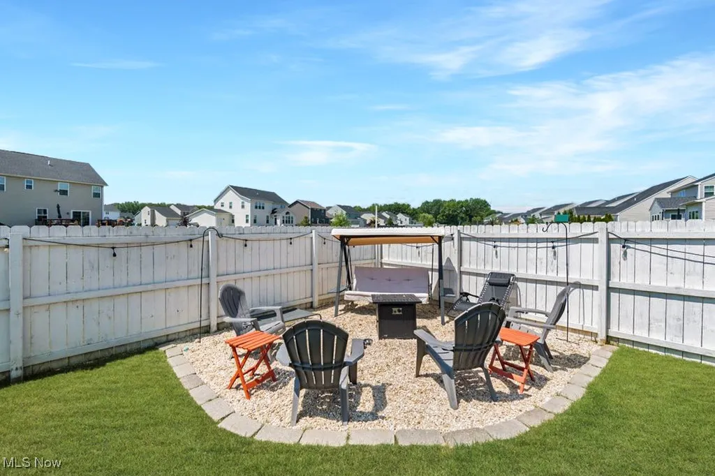 Fenced backyard featuring a fire pit and a residential view