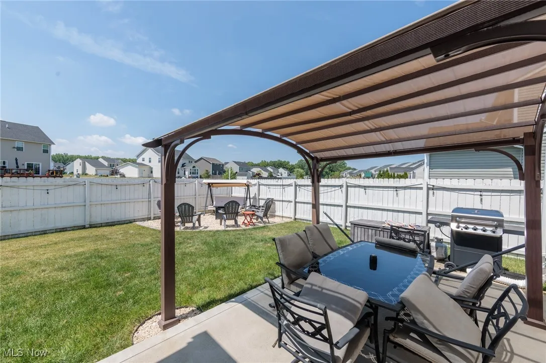 Fenced backyard featuring grilling area, a patio area, a fire pit, a residential view, and outdoor dining space