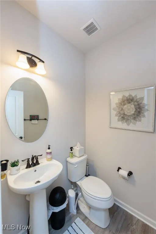 Half bathroom featuring toilet and wood finished floors