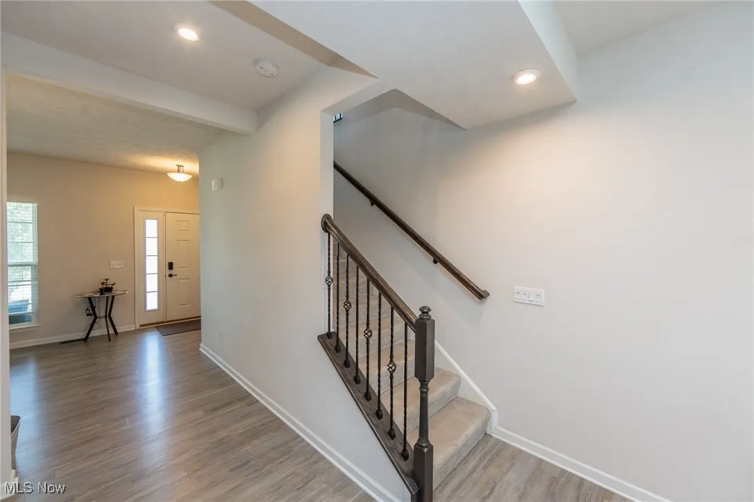 Stairs with wood finished floors and recessed lighting