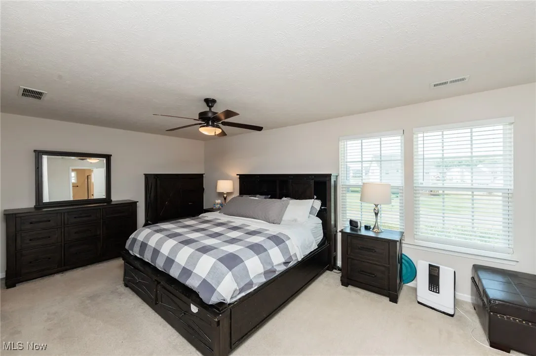 Bedroom with light colored carpet and a ceiling fan