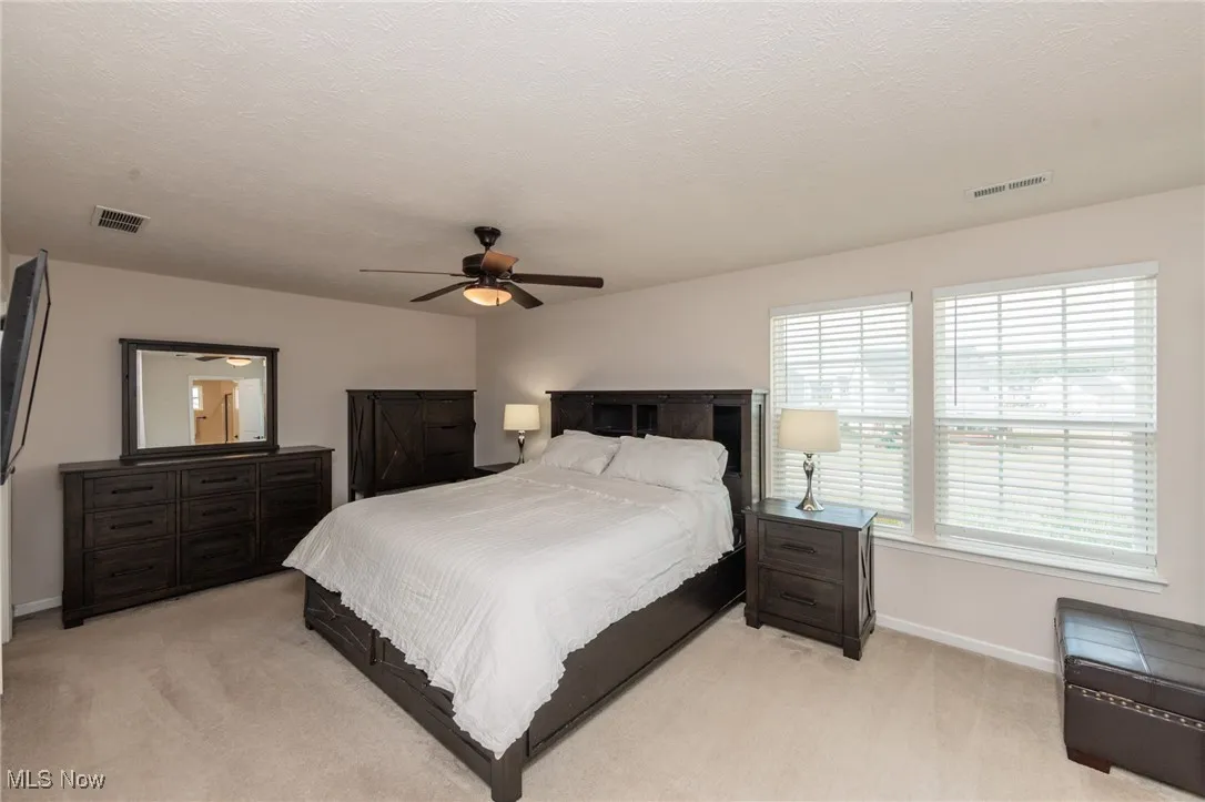 Bedroom featuring light carpet, a textured ceiling, and a ceiling fan