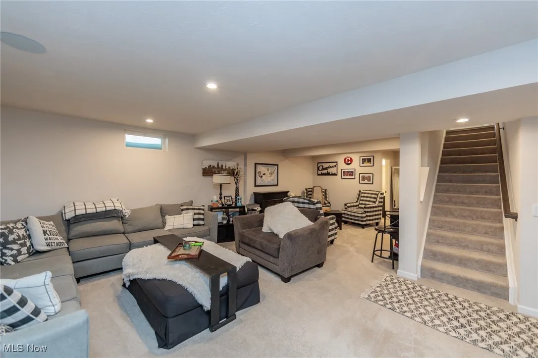 Living room with light colored carpet, stairway, and recessed lighting