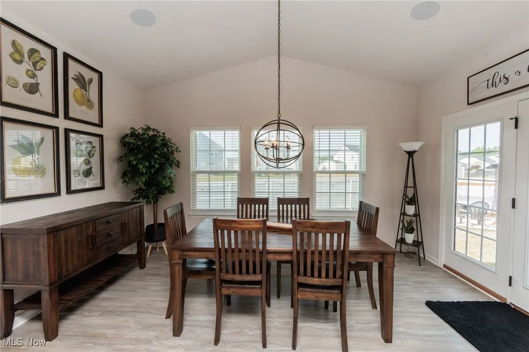 Dining area with a chandelier, light wood-style floors, and lofted ceiling