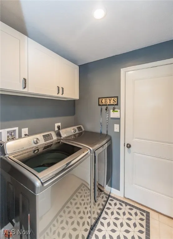 Washroom with cabinet space, washing machine and clothes dryer, recessed lighting, and light tile patterned floors