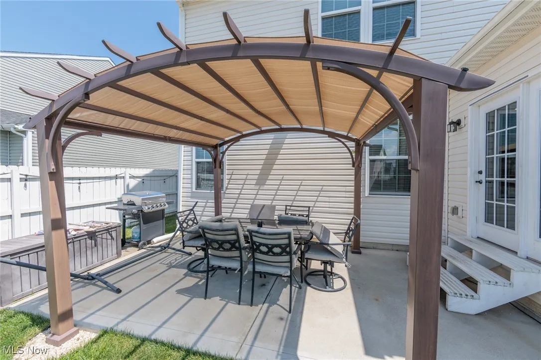View of patio with outdoor dining space, a pergola, grilling area, entry steps, and a detached carport