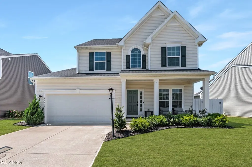 Traditional-style house with driveway, a porch, a front yard, and a garage