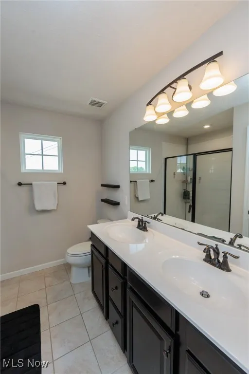 Full bathroom featuring tile patterned flooring, a stall shower, and double vanity