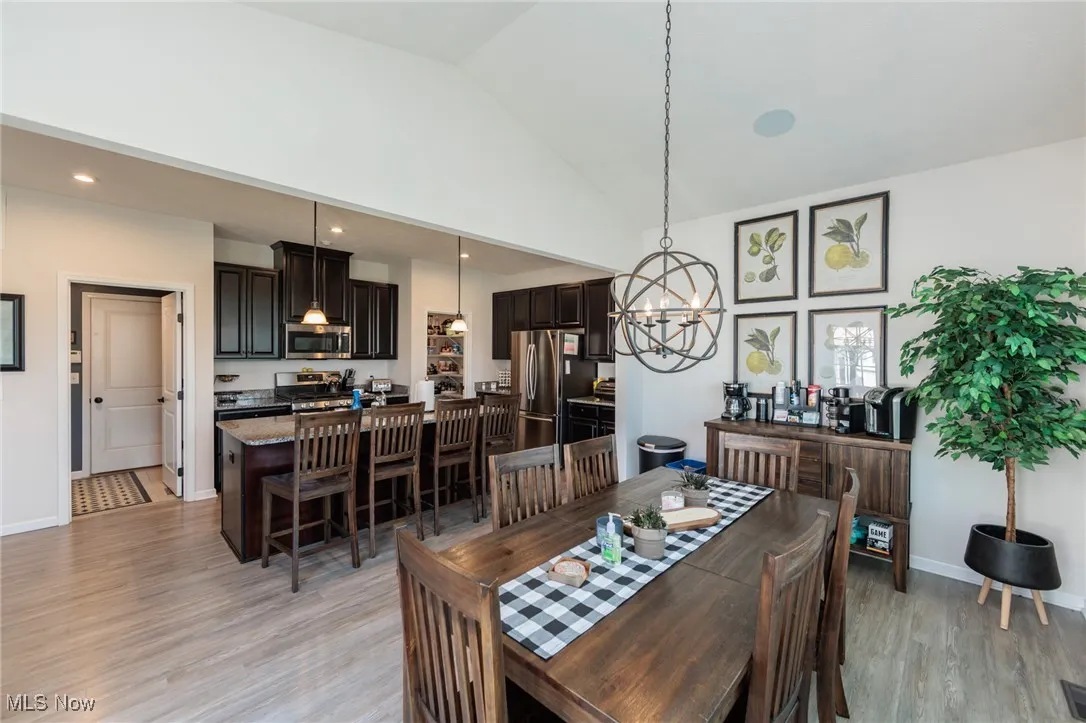 Dining room with a chandelier, light wood-style floors, and high vaulted ceiling