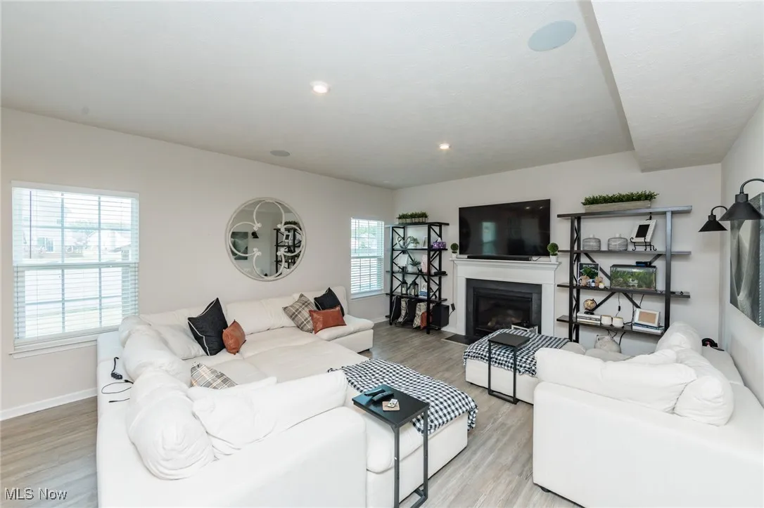 Living room with healthy amount of natural light, light wood-type flooring, a fireplace with flush hearth, and recessed lighting