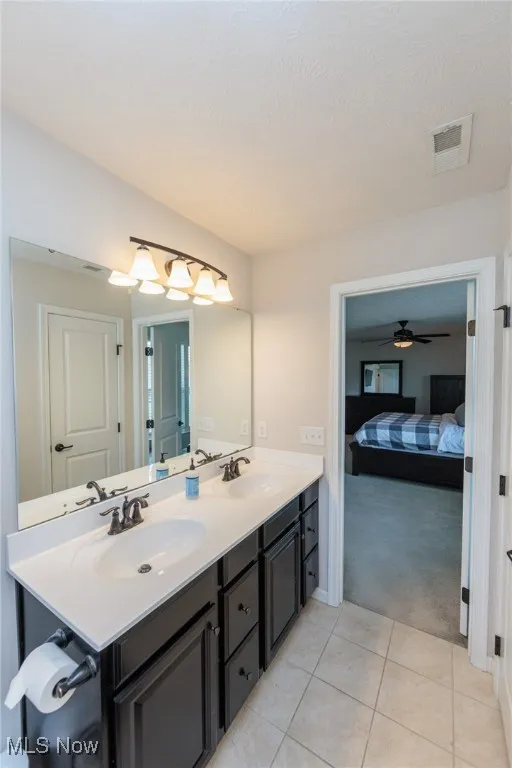 Bathroom with ensuite bath, double vanity, tile patterned flooring, and ceiling fan