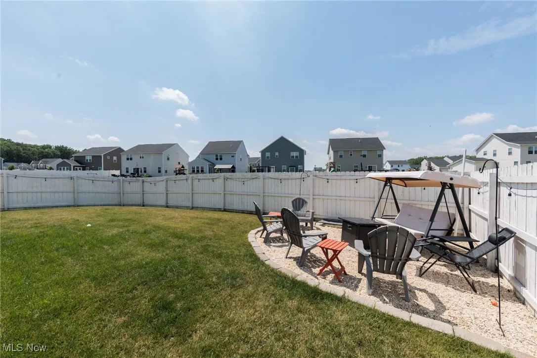 Fenced backyard featuring a residential view and an outdoor fire pit