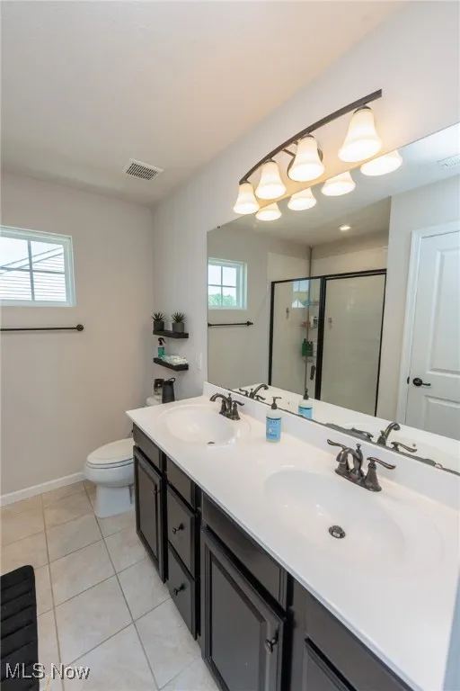 Bathroom with a shower stall, double vanity, and tile patterned floors