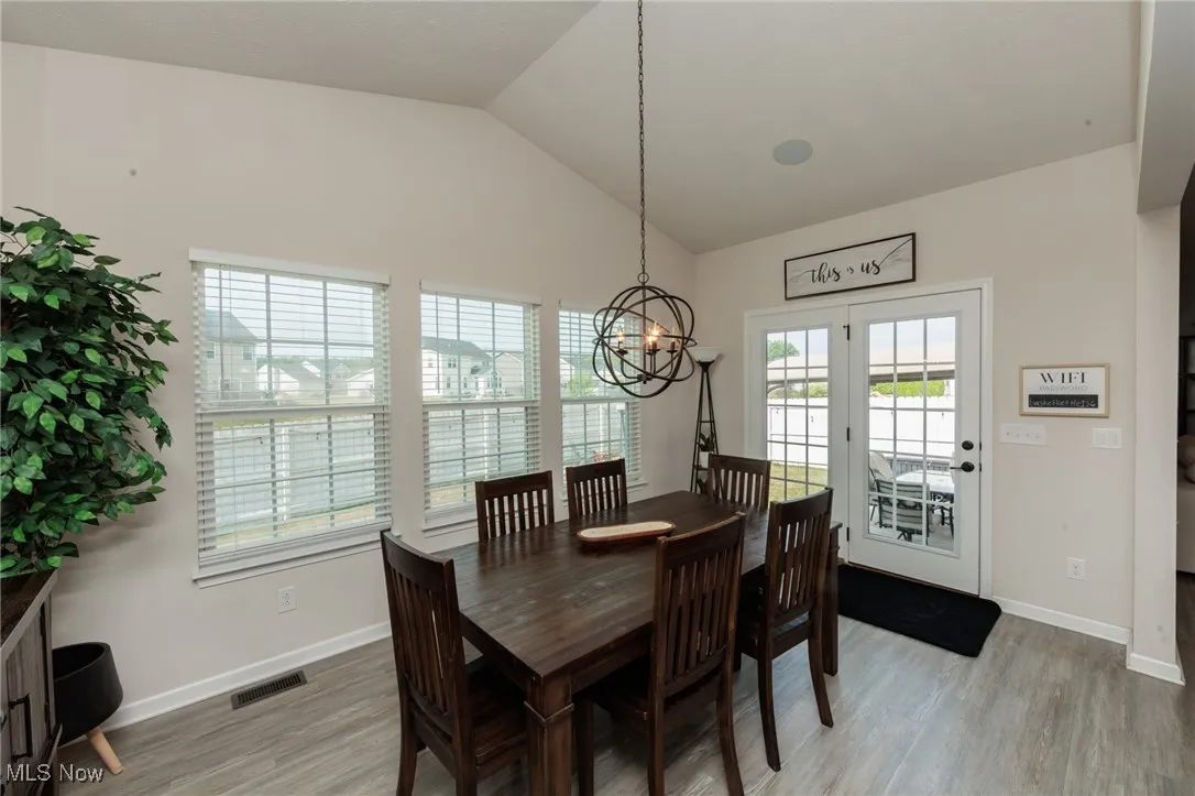 Dining area with lofted ceiling, a chandelier, and light wood-style floors