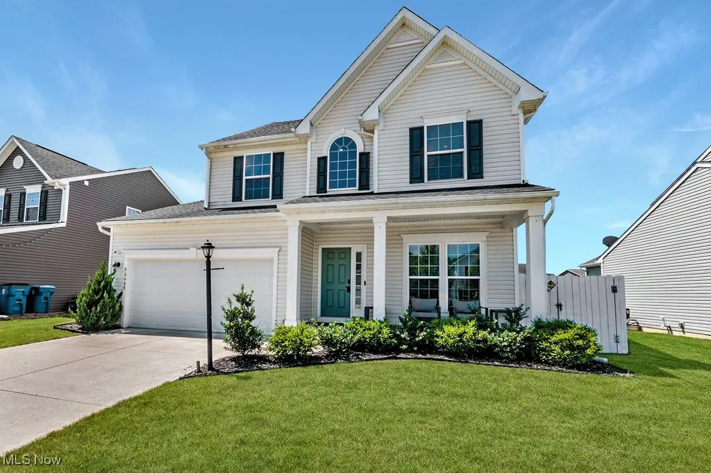 Traditional home with concrete driveway, a front lawn, a garage, and a porch