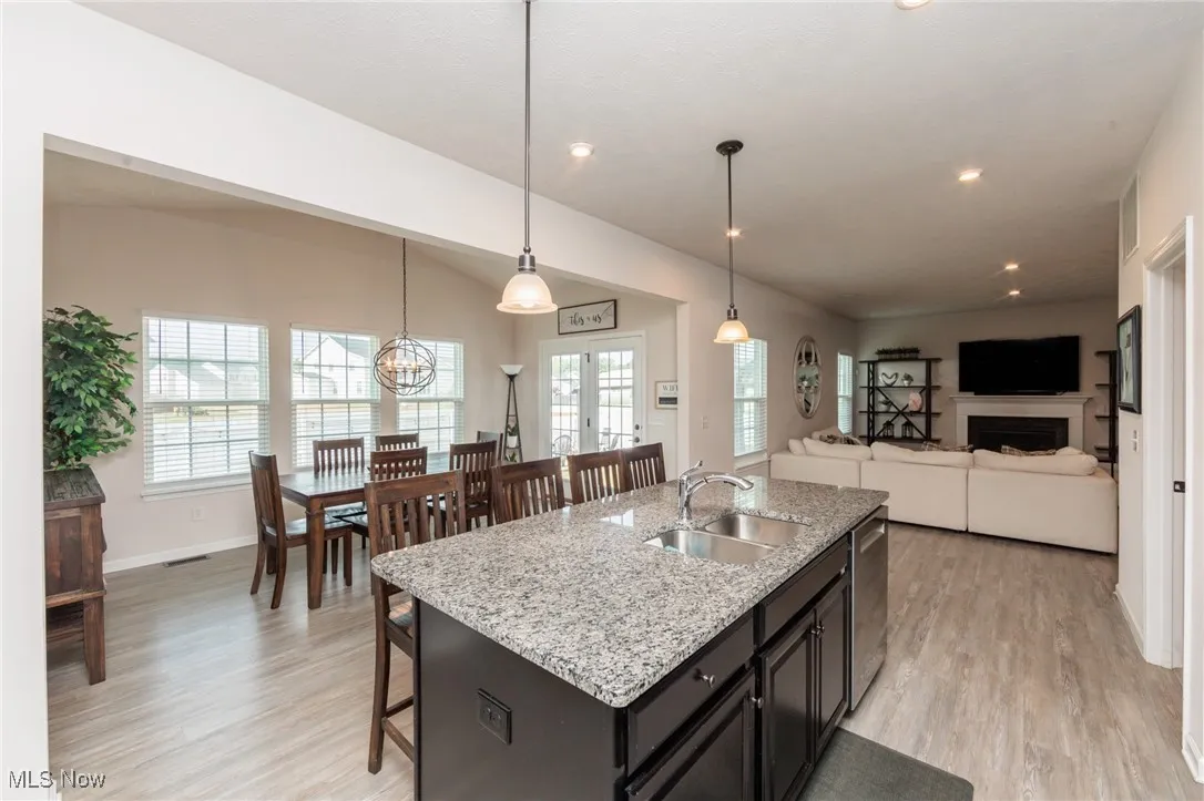 Kitchen featuring plenty of natural light, light wood finished floors, a breakfast bar area, light stone countertops, and recessed lighting