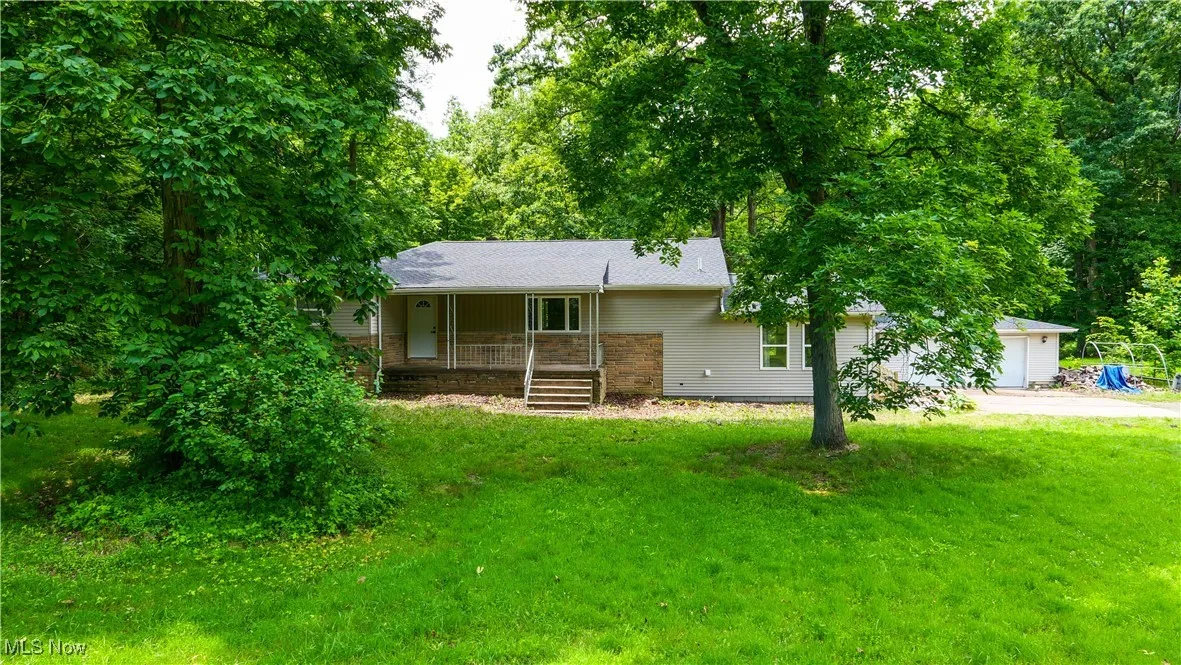 Ranch-style house with concrete driveway, a front yard, a porch, and a garage