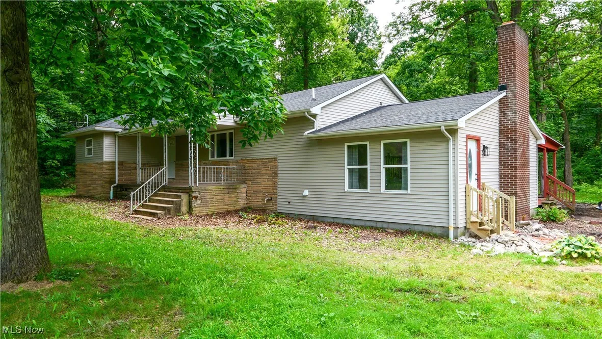 View of front facade featuring covered porch, a chimney, entry steps, a shingled roof, and a front yard