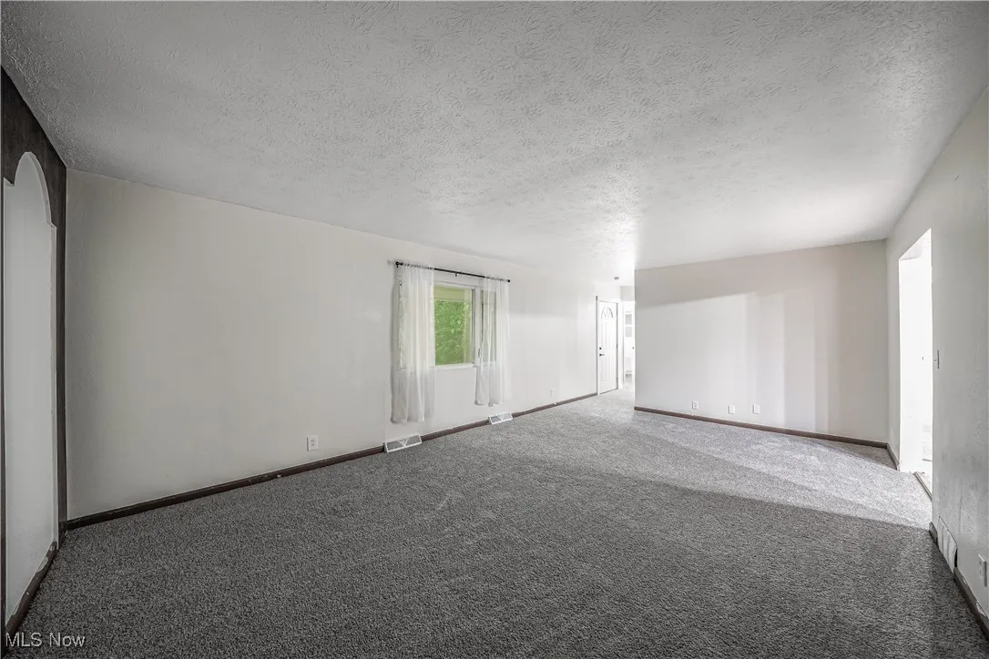 Carpeted empty room with a textured ceiling