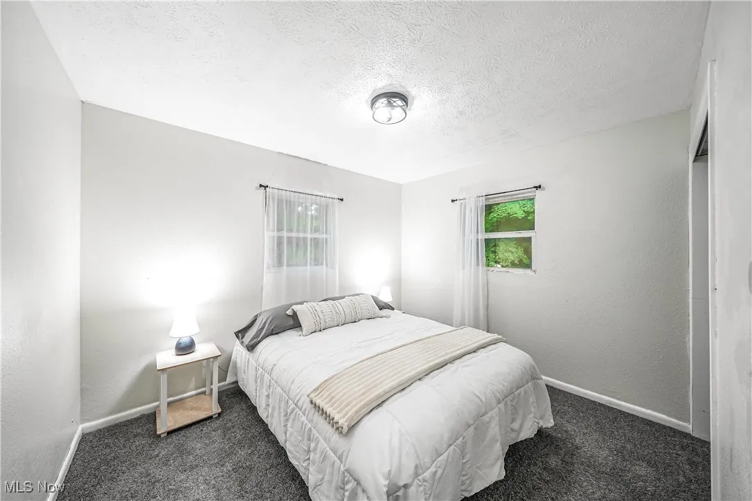 Carpeted bedroom featuring baseboards and a textured ceiling