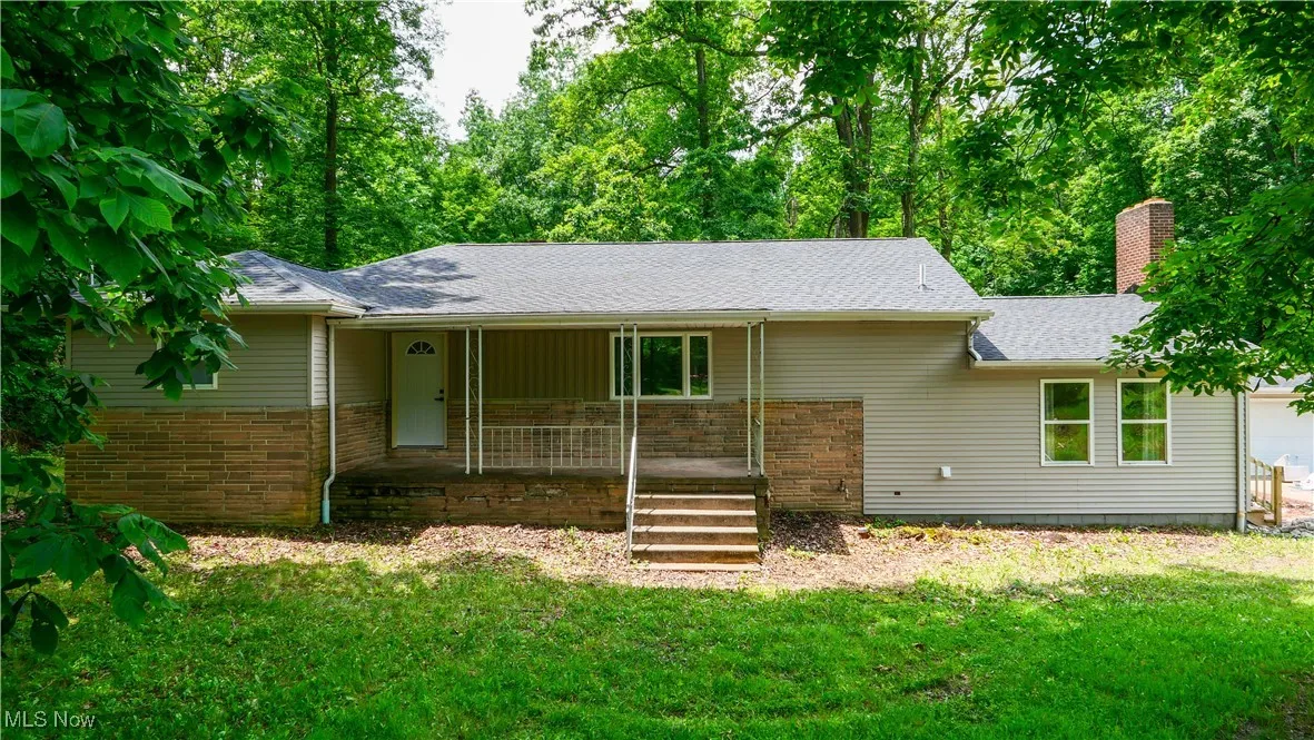 Single story home featuring a porch, a front lawn, a chimney, and roof with shingles