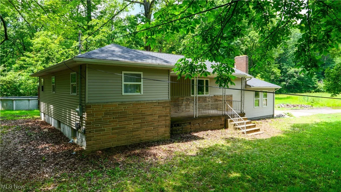 Back of property with a chimney, a shingled roof, a lawn, and brick siding