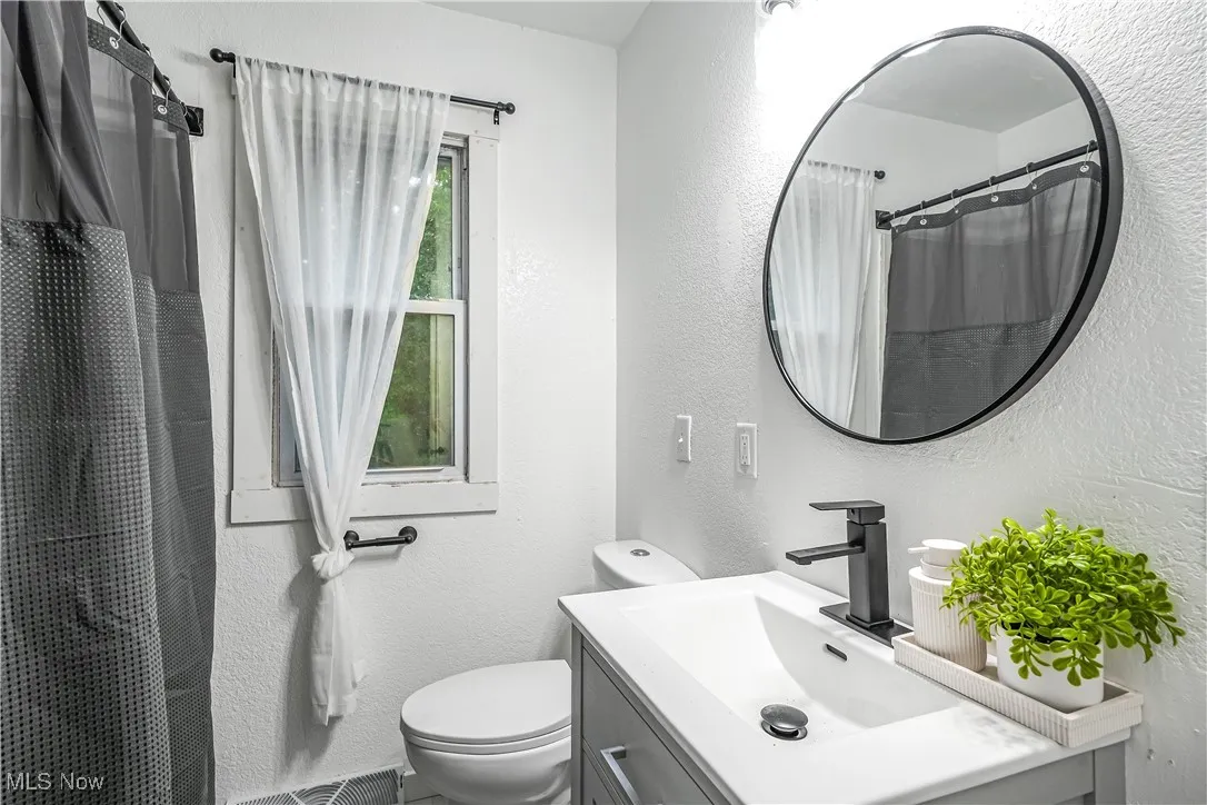 Full bath featuring vanity, a textured wall, and a shower with curtain