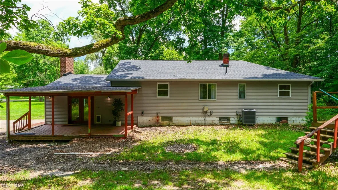 Back of house featuring a chimney, a shingled roof, a wooden deck, and a yard