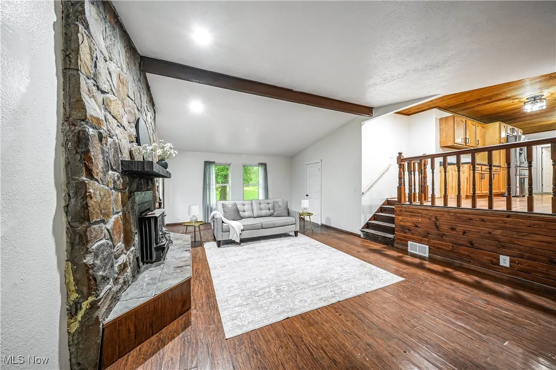 Living room with stairway, a stone fireplace, wood finished floors, and recessed lighting