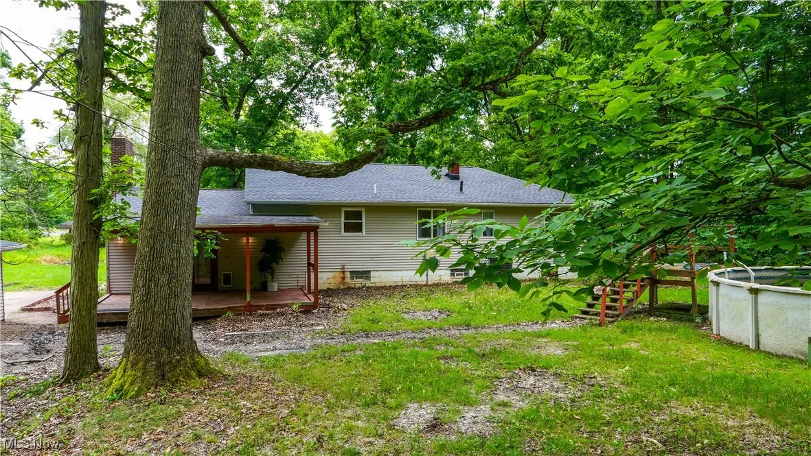 Rear view of property with a wooden deck, a chimney, and roof with shingles