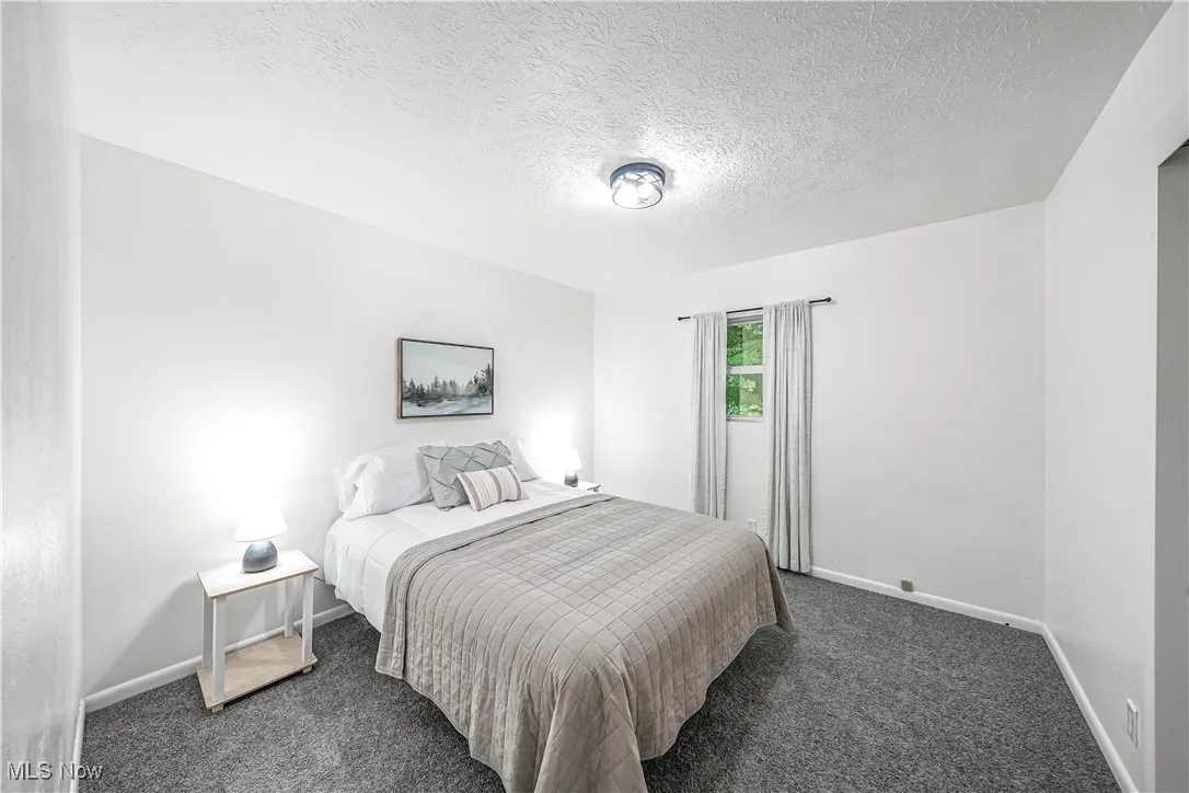 Carpeted bedroom featuring baseboards and a textured ceiling