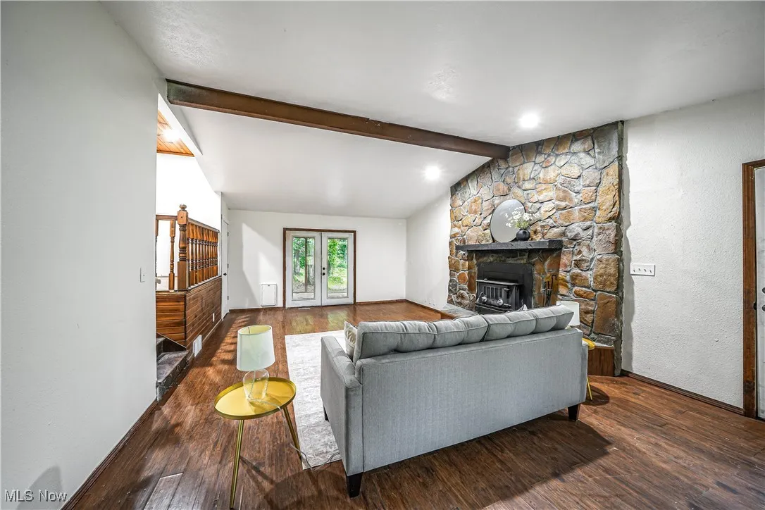 Living room with wood finished floors, stairs, a fireplace, and french doors