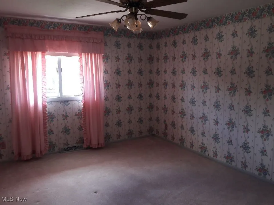 Carpeted spare room with ceiling fan and wallpapered walls