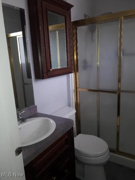 Full bathroom featuring a stall shower, vanity, and tile patterned floors