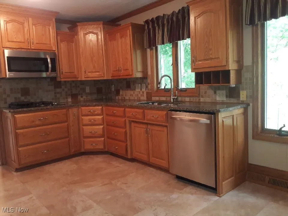 Kitchen featuring appliances with stainless steel finishes, backsplash, and healthy amount of natural light