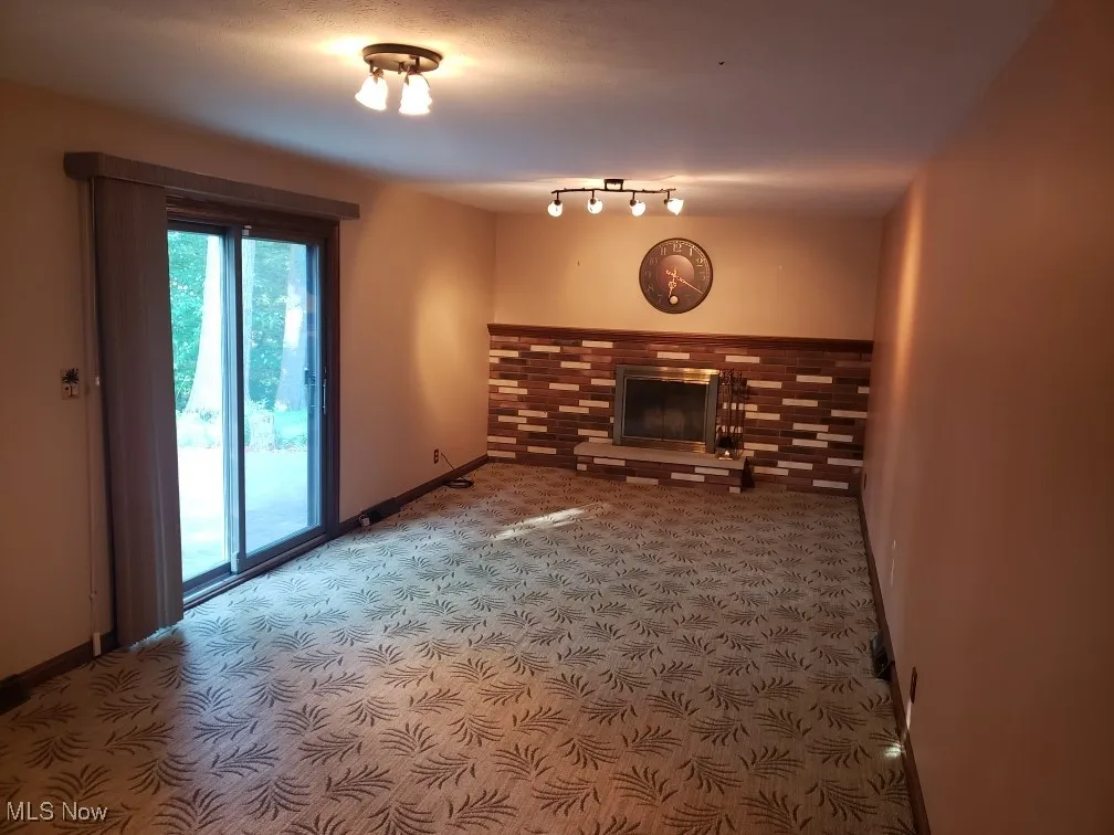 Unfurnished living room with carpet and a glass covered fireplace