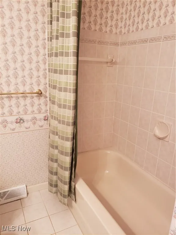 Bathroom with tile patterned flooring, shower / bath combo with shower curtain, and wallpapered walls