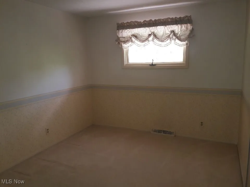 Unfurnished room featuring wainscoting