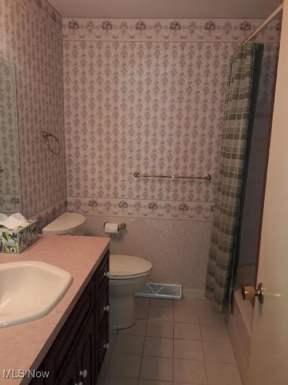 Bathroom with tile patterned floors, vanity, and shower / bathtub combination with curtain