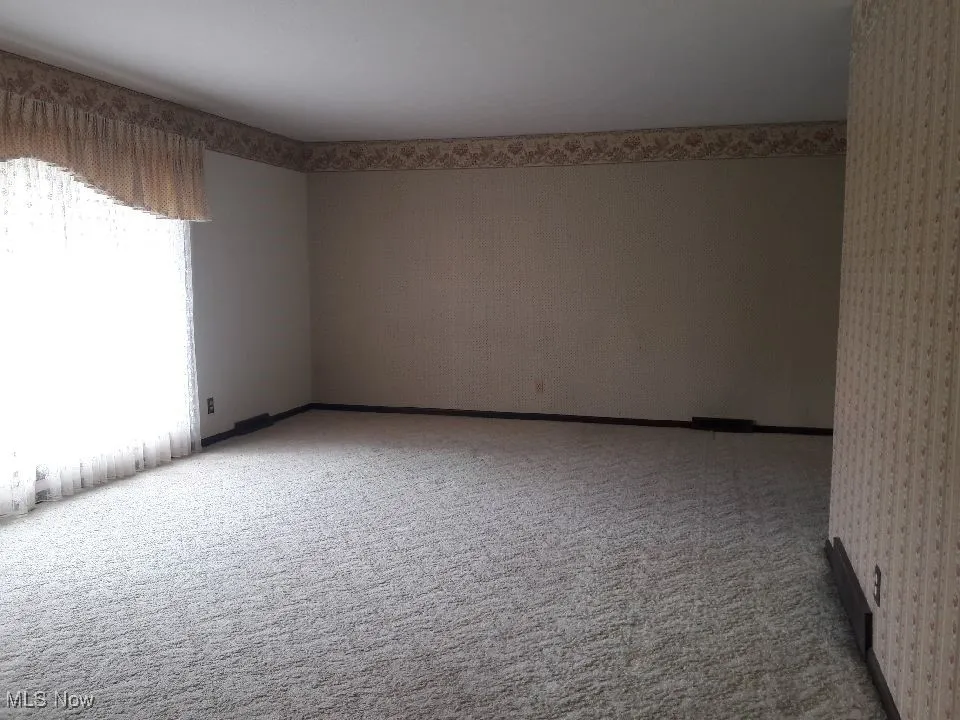 Empty room featuring light carpet and wallpapered walls