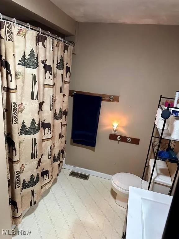 Full bathroom with curtained shower, vanity, and tile patterned floors