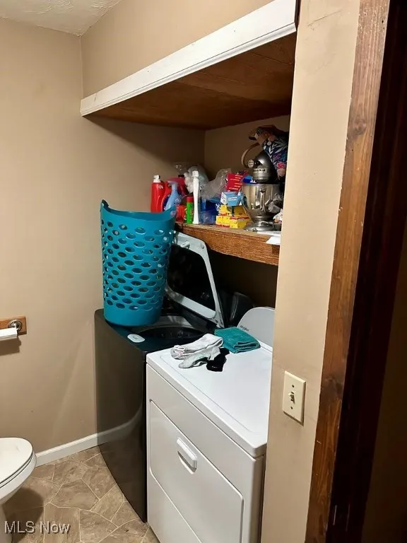 Washroom with washer and clothes dryer and baseboards
