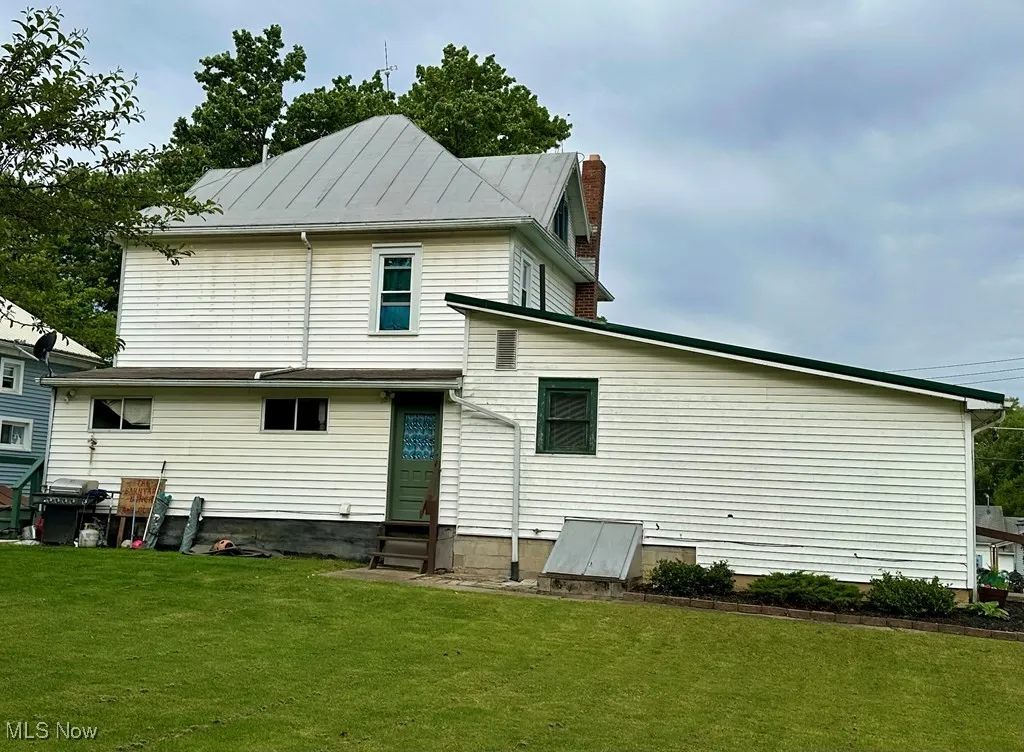 Back of property with entry steps, a yard, and a chimney