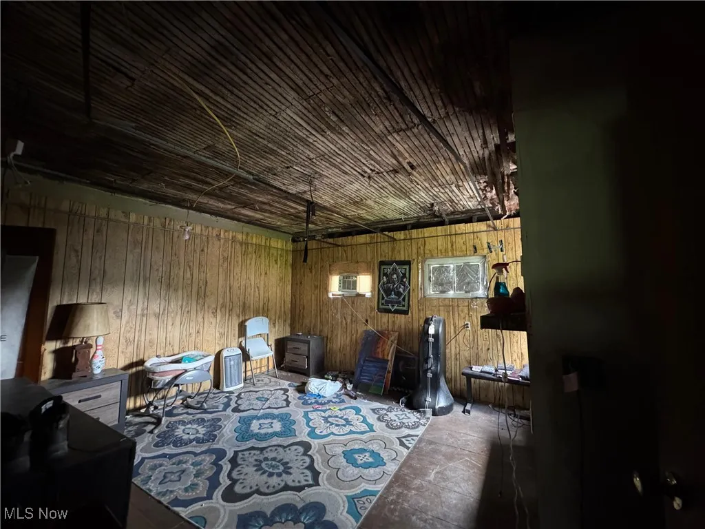 Sitting room with wood walls, a garage, a wall unit AC, and concrete floors
