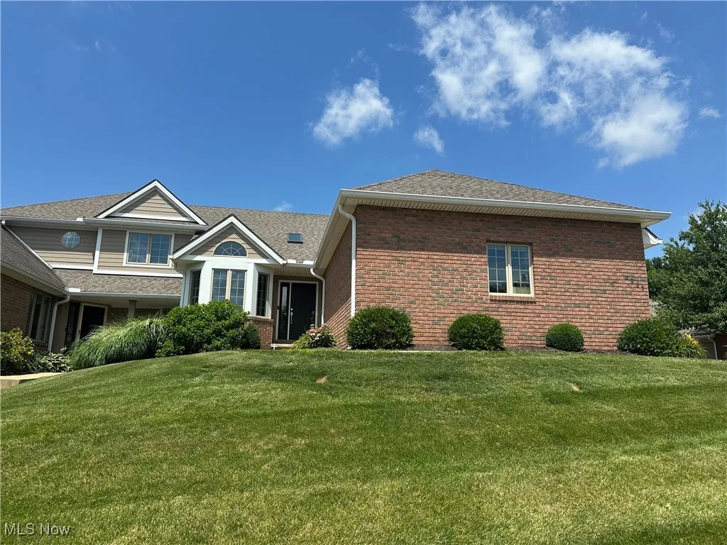 View of front of property featuring brick siding, a front lawn, and a shingled roof