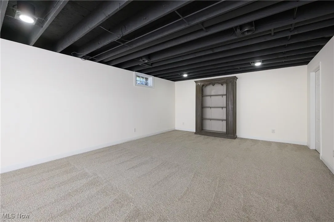 Below grade area featuring light carpet and baseboards