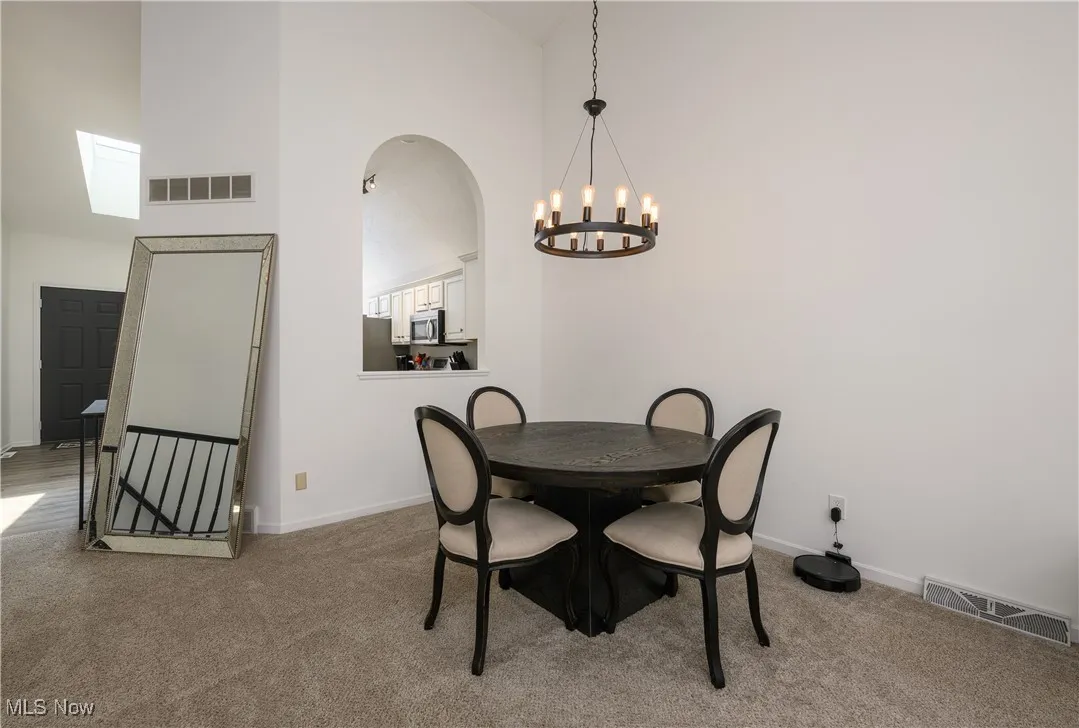 Dining area featuring high vaulted ceiling, a chandelier, carpet flooring, and arched walkways