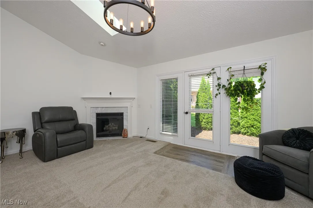 Carpeted living area featuring a chandelier and a fireplace