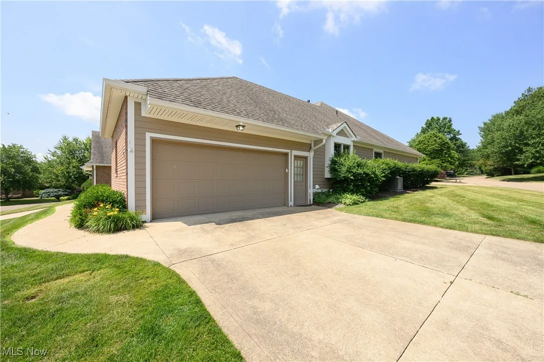View of front facade with concrete driveway, a garage, a front yard, and a shingled roof