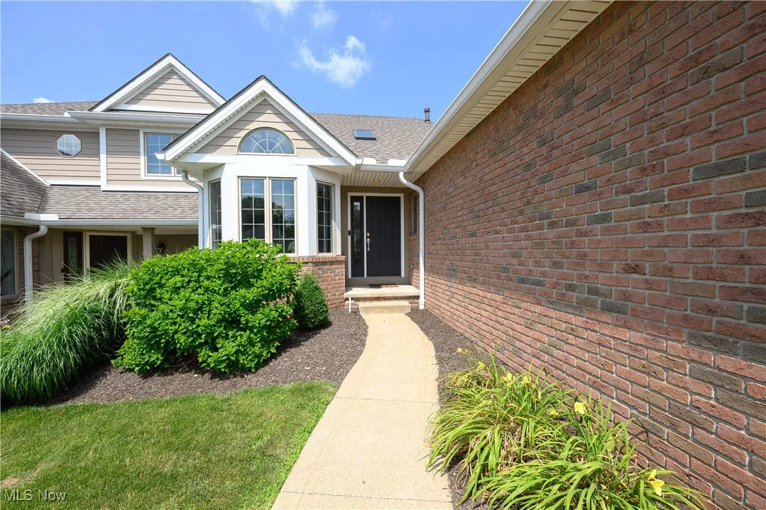 Doorway to property featuring roof with shingles and brick siding